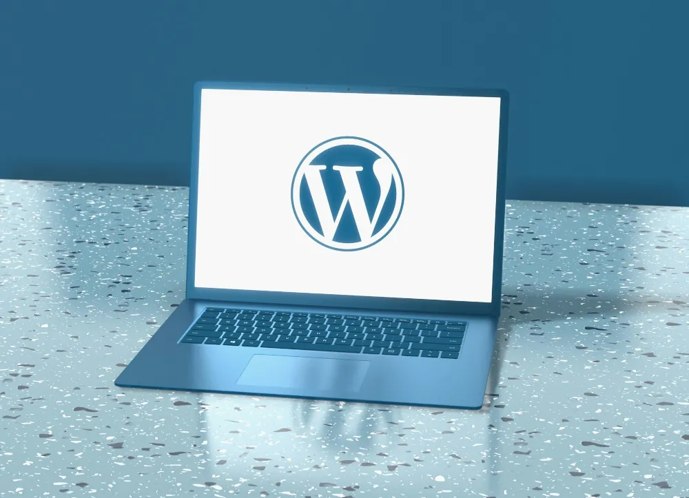 Notebook sobre un escritorio mostrando el logo de WordPress en la pantalla